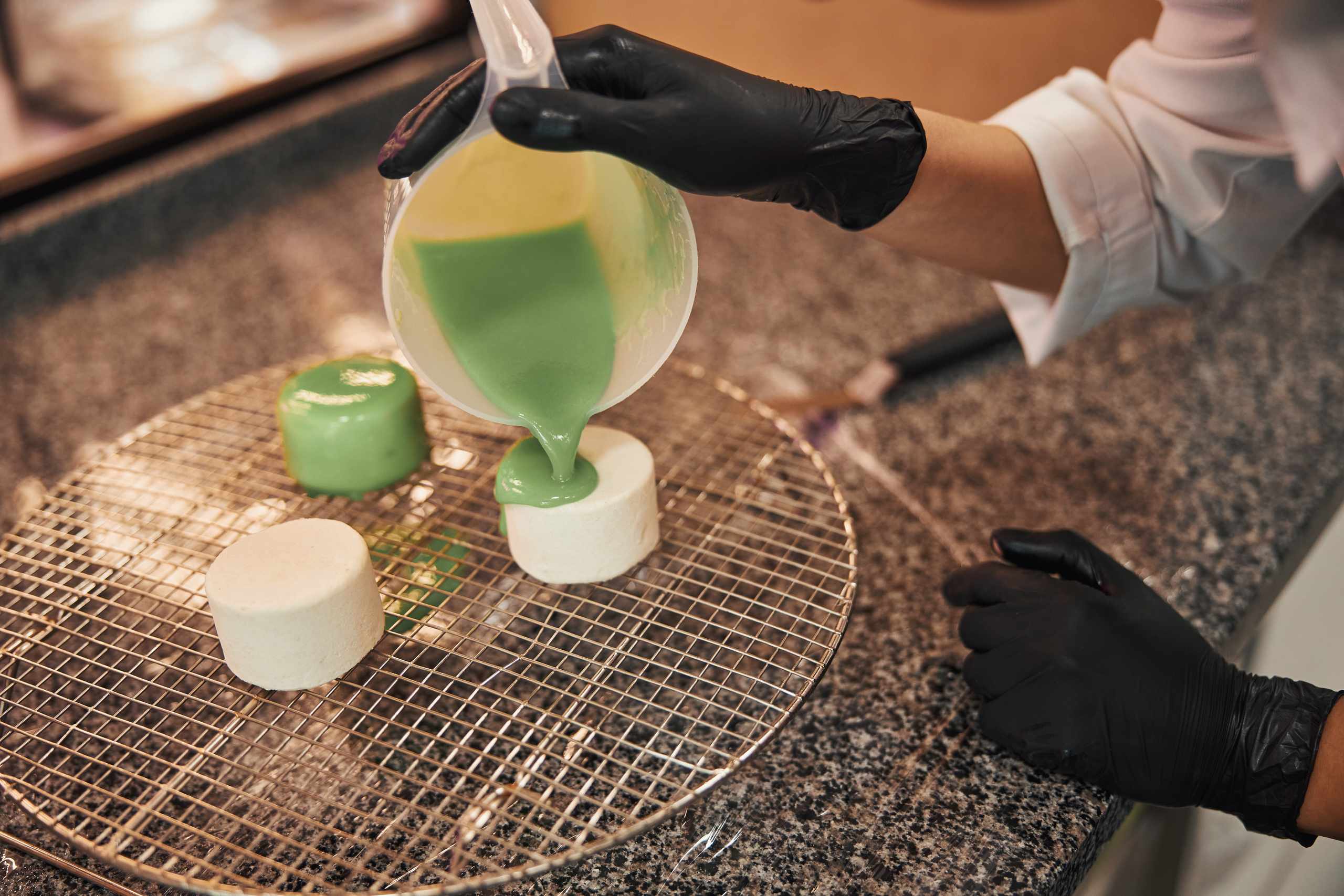 Green glaze being poured onto cakes