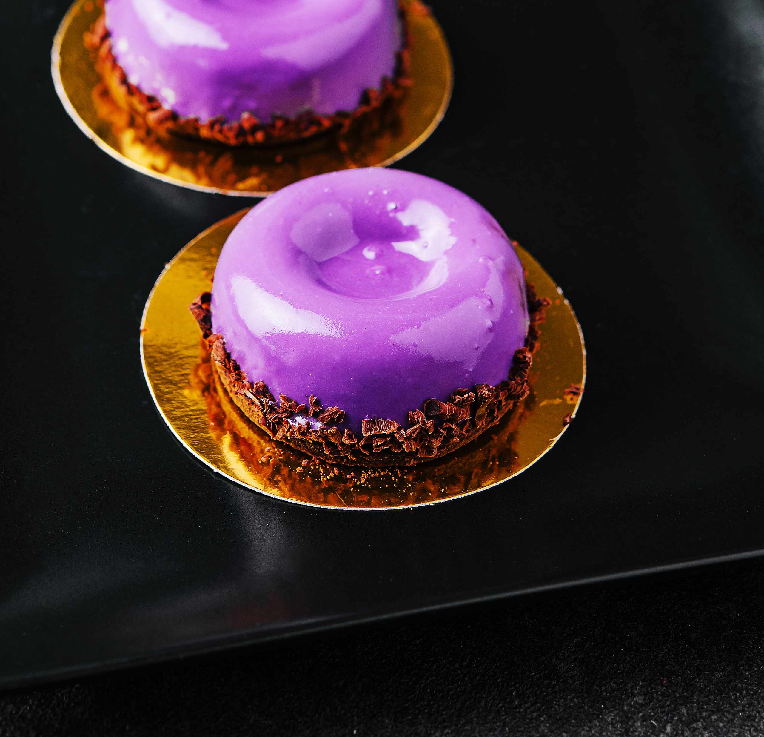 Purple glazed desserts on a dark surface